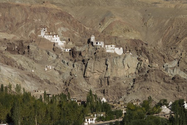 Basgo Gompa, the Buddhist monastery and fortress in Central Ladakh, with the village below it and rugged mountain landscape around. Photographed on a sunny day in September, the late summer. Many inhabitants of this Indian region, which is often called Little Tibet, follow the Tibetan Buddhism. Leh District, Union Territory of Ladakh, India, Asia