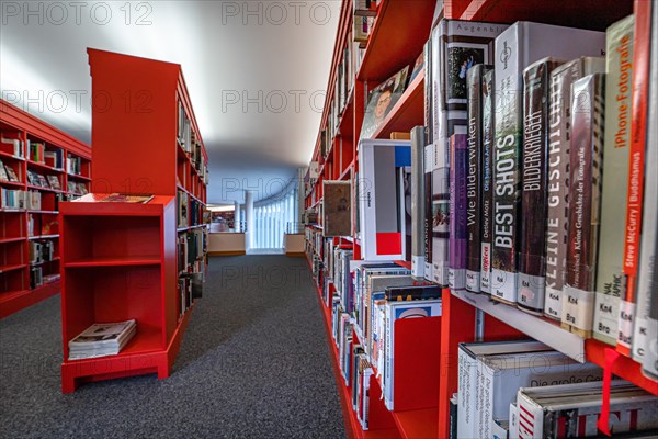 Interior view of a library with red shelves full of books, Pforzheim, Germany, Europe