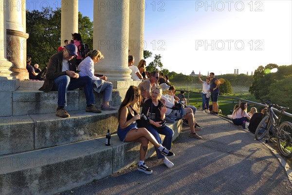 People enjoying the autumn sun at the Monopteros in the English Garden, with a view of the Munich skyline, Munich, Bavaria, Germany, Europe