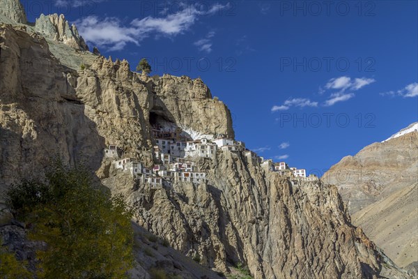 Phugtal Gompa, one of the most spectacularly located Buddhist monasteries of Ladakh, which clings to a mountain cliff, high above the valley floor. It belongs to the Gelug school of the Tibetan Buddhism. Photographed on a sunny, blue-sky day in late September, autumn. Zanskar Range of the Himalayas. Kargil District, Union Territory of Ladakh, India, Asia