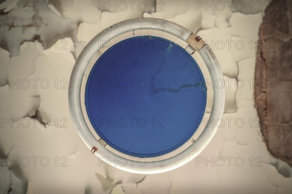 A close-up view of a round hatch window with blue eggshell texture showing cracks, Urologist's Villa Dr Anna L., Lost Place, Bad Wildungen, Hesse, Germany, Europe