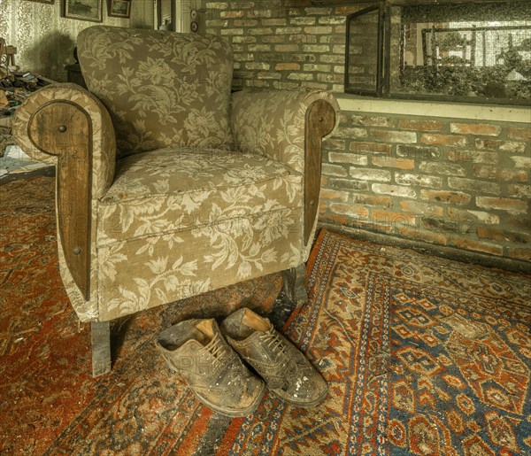 An armchair and a pair of old shoes in a room with a brick wall, Maison Limmi, Lost Place, Kalken, Laarne, Province of East Flanders, Belgium, Europe