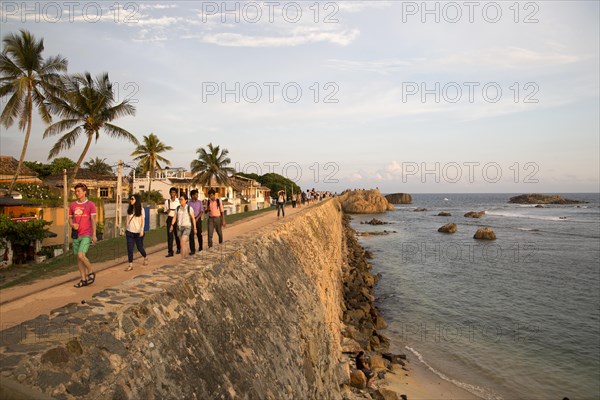 Tourists walk on fort ramparts in historic town of Galle, Sri Lanka, Asia