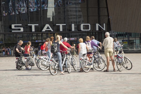 Group of cyclists outside central railway station building, Centraal Station, Rotterdam, Netherlands