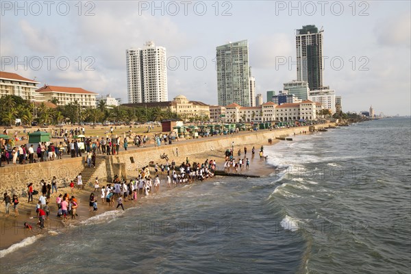 School children paddle in the sea on small sandy beach at Galle Face Green, Colombo, Sri Lanka, Asia