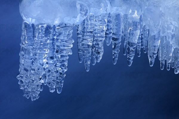 Ice formations and icicles formed by frost and freezing cold temperatures over running water of stream