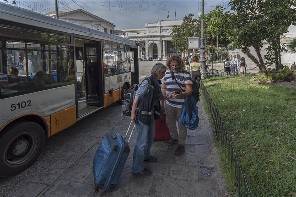 Tourists with Iphones at a bus stop, railway station in Genoa, Italy, Europe