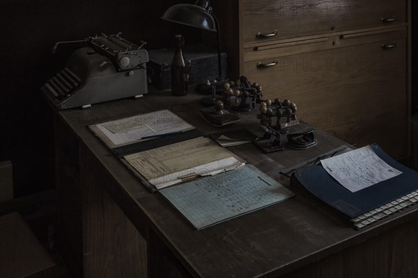 An old office with antique typewriter and desk lamp in the semi-darkness, Dahlhausen railway depot, Lost Place, Dahlhausen, Bochum, North Rhine-Westphalia, Germany, Europe