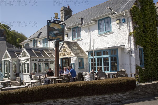 People sitting outside The Rising Sun pub, St Mawes, Cornwall, England, UK