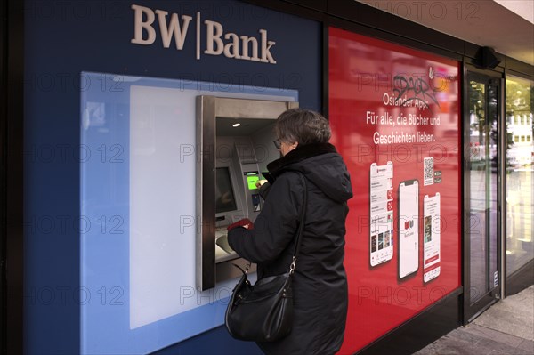 Elderly woman, best ager, inserts EC card, credit card, PIN, purse, ATM of BW-Bank Baden-Wuerttembergische Bank, logo, Stuttgart, Baden-Wuerttemberg, Germany, Europe