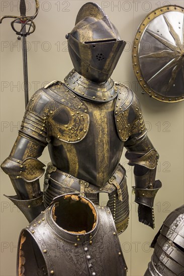 16th century browned and gilded medieval suit of armour with armet, burgonet helmet, burgundian sallet at the Royal Museum of the Army and of Military History in Brussels, Belgium, Europe