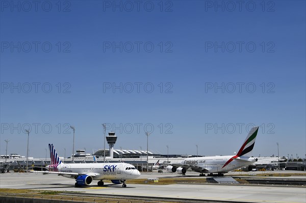 Sky Express Airbus A320 Neo and Emirates Airways Airbus A380-800 taxiing on apron in front of Terminal 1 with tower, Munich Airport, Upper Bavaria, Bavaria, Germany, Europe
