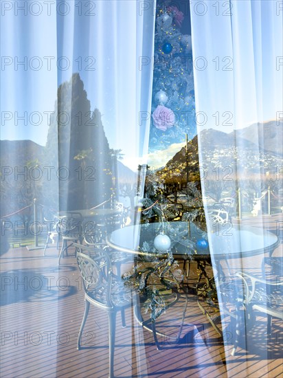 Christmas Tree with Window Reflection and View over a Terrace and Tree and Mountain in Lugano, Ticino, Switzerland, Europe
