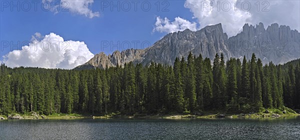 The lake Lago di Carezza, Karersee surrounded bij mountain peaks and pine forest in the Dolomites, Italy, Europe