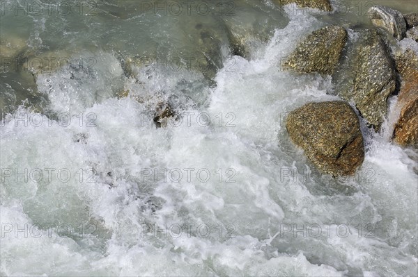 Glacial water flowing fast over boulders in alpine mountain stream, Swiss Alps, Switzerland, Europe