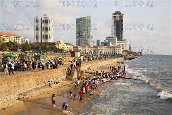 School children paddle in the sea on small sandy beach at Galle Face Green, Colombo, Sri Lanka, Asia