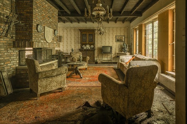 Abandoned-looking living room with worn furniture and caved-in floor, Maison Limmi, Lost Place, Kalken, Laarne, Province of East Flanders, Belgium, Europe