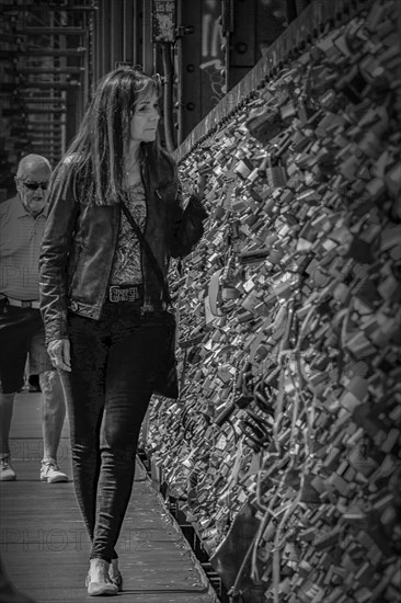 Woman walking along a bridge with many padlocks, black and white photograph, Hohenzollern Bridge, Cologne Deutz, North Rhine-Westphalia, Germany, Europe