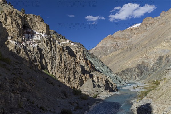 Phugtal Gompa, one of the most spectacularly located Buddhist monasteries of Ladakh, which clings to a mountain cliff, high above Tsarab Chu, the river that cuts across the Zanskar Range of the Himalayas. The monastery belongs to the Gelug school of the Tibetan Buddhism. Photographed on a sunny, blue-sky day in late September, autumn. Kargil District, Union Territory of Ladakh, India, Asia