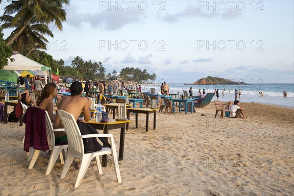 People sitting at tables of beach bar, Mirissa, Sri Lanka, Asia