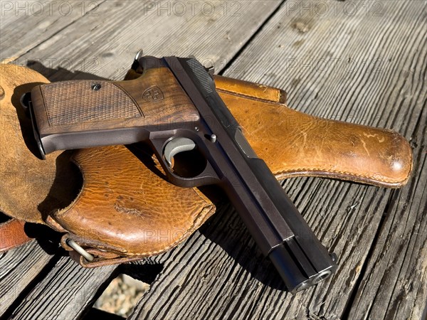 Elegant Old Handgun on an Old Wood Table with Holster in a Sunny Day, Made in Switzerland
