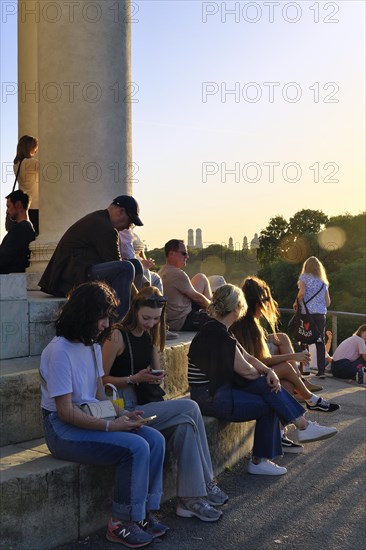 People enjoying the autumn sun at the Monopteros in the English Garden, with a view of the Munich skyline, Munich, Bavaria, Germany, Europe
