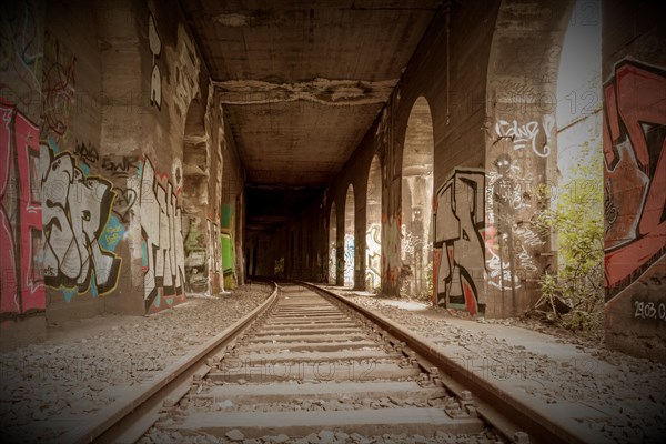 Symmetrical view through a tunnel with tracks, walls sprayed with graffiti, former railway branch Rethel, Lost Place, Flingern, Duesseldorf, North Rhine-Westphalia, Germany, Europe