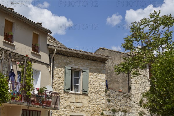 Old sandstone-walled houses with windows, shutters, balcony and a balcony in Goudargues, Gard department, Occitanie region, France, Europe