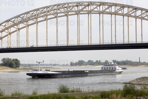 Barge beneath Waalbrug bridge, River Waal, Nijmegen, Gelderland, Netherlands