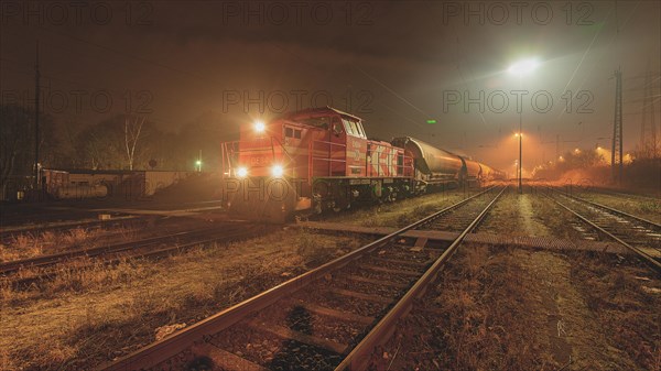 A red diesel locomotive stands on illuminated tracks at night, Ruhr area, North Rhine-Westphalia, Germany, Europe