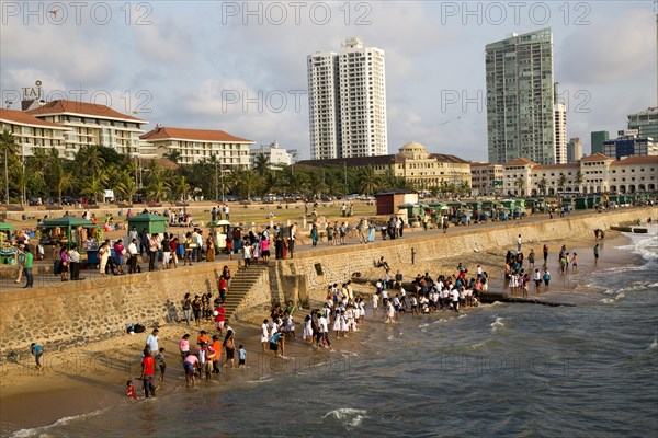 School children paddle in the sea on small sandy beach at Galle Face Green, Colombo, Sri Lanka, Asia