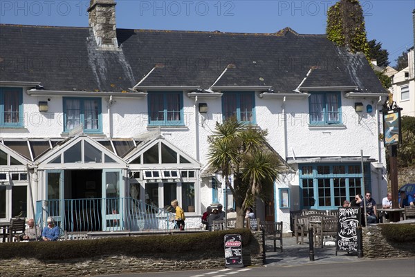 People sitting outside The Rising Sun pub, St Mawes, Cornwall, England, UK