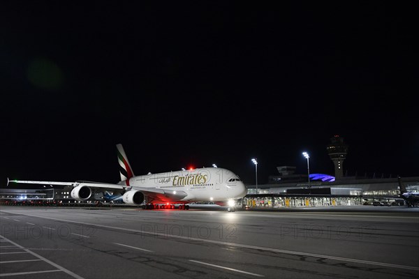 Emirates Airlines Airbus A38-800 taxiing on apron in front of Terminal 1 with tower at night, Munich Airport, Upper Bavaria, Bavaria, Germany, Europe