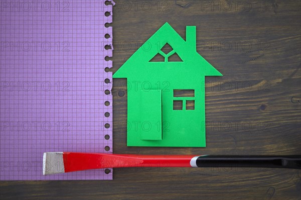 Green cutout of model house with hand tool on a memo notepad in a concept of home ownership, renovation or construction