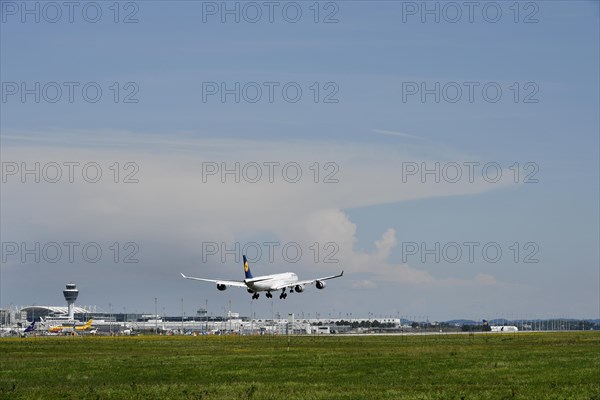 Lufthansa Airbus A340 landing on southern runway, with thundercloud and storm front in the background, terminal and tower, Munich Airport, Upper Bavaria, Bavaria, Germany, Europe