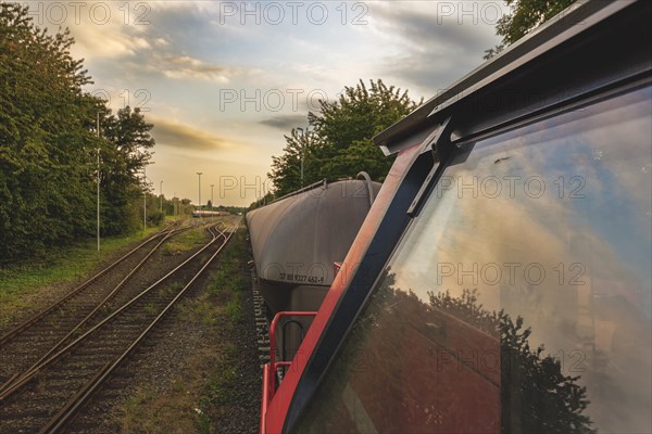 View from the rear-view mirror of a locomotive onto a goods train and tracks in the evening light, Lower Rhine, North Rhine-Westphalia, Germany, Europe
