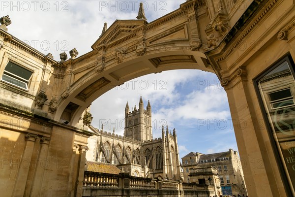 View of abbey church and Roman Baths from under stone archway, York Street, Bath, Somerset, England, UK