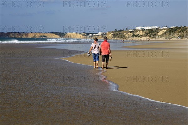 Man and woman walking together on sandy beach at Conil de la Frontera, Cadiz Province, Spain, Europe