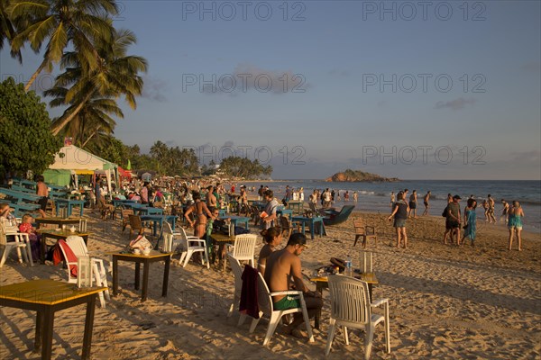 People sitting at tables of beach bar, Mirissa, Sri Lanka, Asia