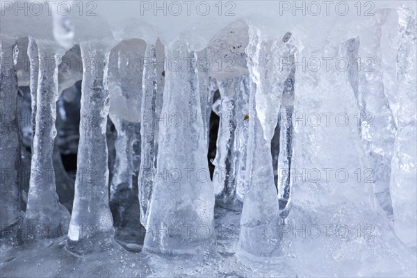Ice formations and icicles formed by frost and freezing cold temperatures over running water of stream