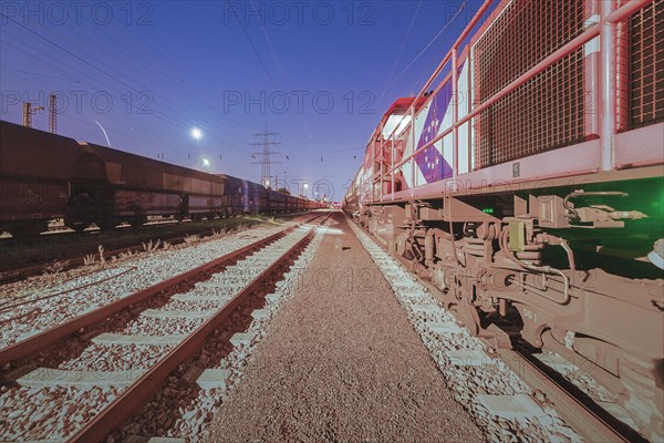 Red locomotive and wagons standing on tracks at night under artificial light, Ruhr area, North Rhine-Westphalia, Germany, Europe