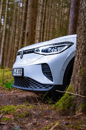 White Deer Carsharing electric car from Volkswagen partially covered by a tree in the forest, Unterhaugstett, Black Forest, Germany, Europe