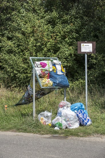 Illegal dumping of household refuse bags in net along roadside meant for throwing in cans and plastic bottles