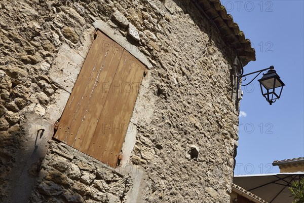 Facades of old sandstone houses with shutters and a street lamp in Goudargues, Departement Gard, Occitanie region, France, Europe