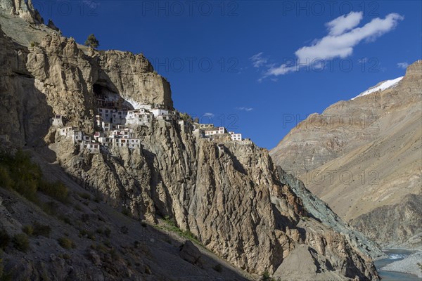 Phugtal Gompa, one of the most spectacularly located Buddhist monasteries of Ladakh, which clings to a mountain cliff, high above Tsarab Chu, the river that cuts across the Zanskar Range of the Himalayas. The monastery belongs to the Gelug school of the Tibetan Buddhism. Photographed on a sunny, blue-sky day in late September, autumn. Kargil District, Union Territory of Ladakh, India, Asia