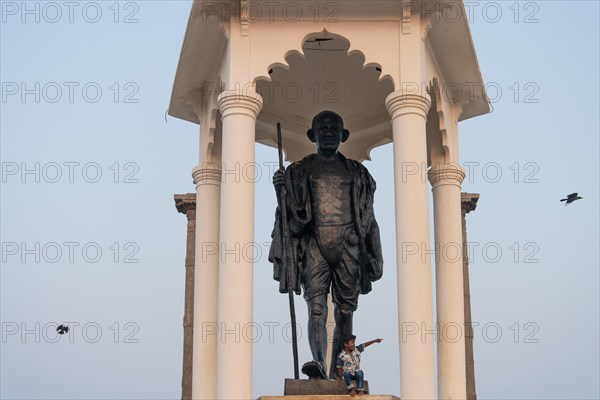 Child at the foot of a Mahatma Gandhi monument, statue, former French colony of Pondicherry or Puducherry, Tamil Nadu, India, Asia