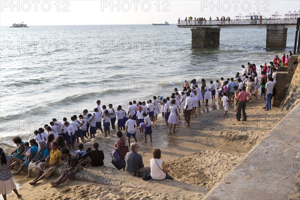 School children paddle in the sea on small sandy beach at Galle Face Green, Colombo, Sri Lanka, Asia