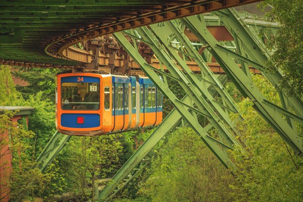 Blue and orange coloured suspension railway on a green track with steel construction, suspension railway, Wuppertal, North Rhine-Westphalia, Germany, Europe