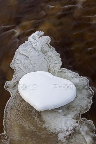 Heart-shaped snow patch on slush ice in river in winter