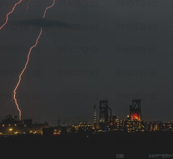 Lightning strikes at night in an urban industrial landscape, illuminated by various lights, Duisburg, North Rhine-Westphalia, Germany, Europe